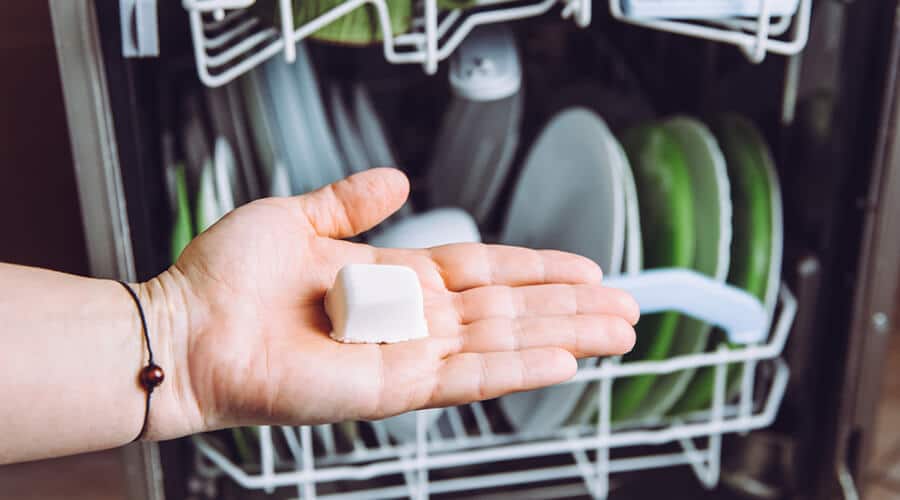 An eco-friendly dishwasher pod being placed in a dishwasher