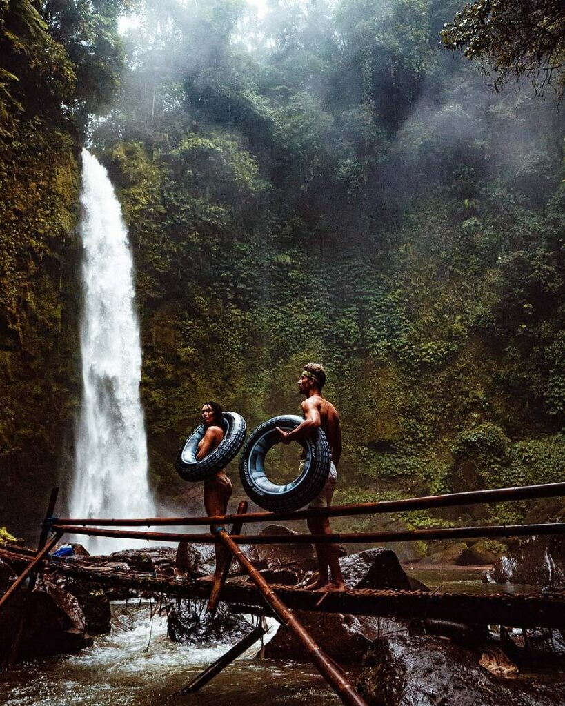 People carrying tyres near a waterfall